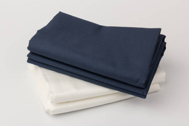 istock Stack of clean white and blue bed sheets on white  background, closeup. 1281245271
