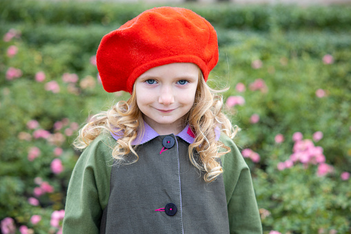 Portrait of a beautiful preschool girl in a red beret. Walk in the autumn season.