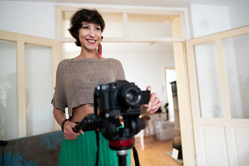 Young, Caucasian camerawoman filming and smiling at home