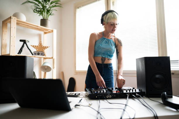 Young female dj and producer practicing mixing music at home Young, tattooed, Caucasian, female dj and producer practicing mixing music at home. making music stock pictures, royalty-free photos & images