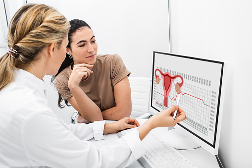 ginecólogo se comunica con su paciente, indicando el ciclo menstrual en el monitor. El especialista en reproducción calculó el período de ovulación para el paciente photo
