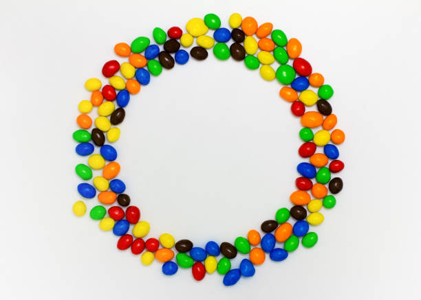 Jar filled with colourful candy coated button shaped milk chocolates studio shot