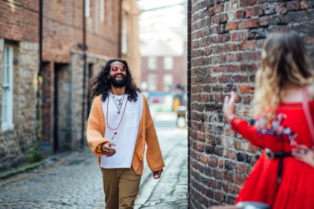 Meeting Up A shot of a mid adult Pakistani man and a young caucasian woman meeting in an urban scene. They are looking and greeting each other with a smile. They are wearing bohemian clothing and accessories. tinted sunglasses stock pictures, royalty-free photos & images