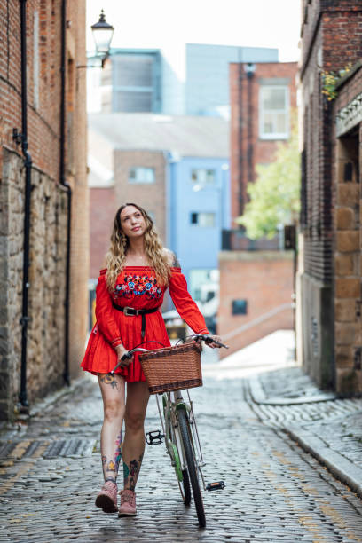 istock Hipster Woman Pushing Bicycle Down Cobbled Street 1281261663