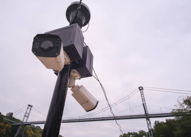 istock Security camera hanging among wire in guarded bridge with cloudy sky background. 1281261989