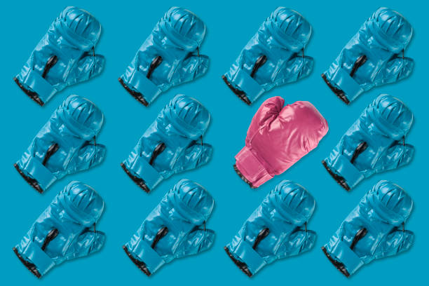 Pattern of a group of blue boxing gloves in which a pink boxing glove stands out. Concept of feminism stock photo