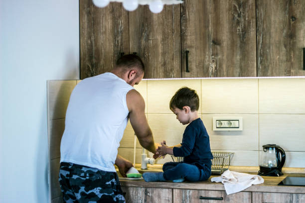 istock Single father teaching son to clean dishes in kitchen. 1281265215