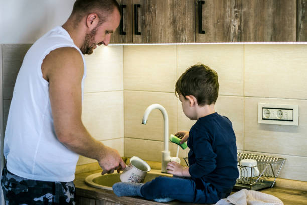 istock Single father teaching son to clean dishes in kitchen. 1281265873