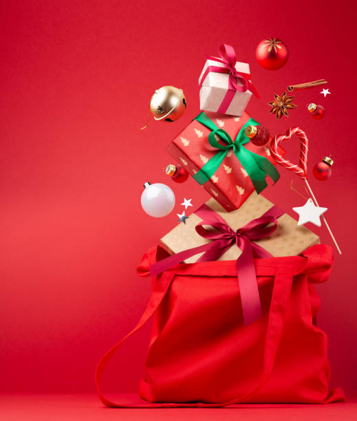 クリスマスショッピング。マジックフライや落下コンセプト。ギフトボックス、キャンディー、シナモン、その他の新年の装飾が施された赤い綿袋。 - christmas bag shopping bag gift ストックフォトと画像
