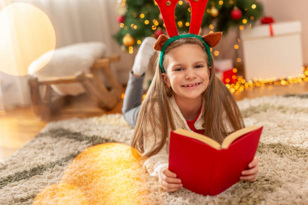 istock Little girl reading a book on Christmas day 1281272103