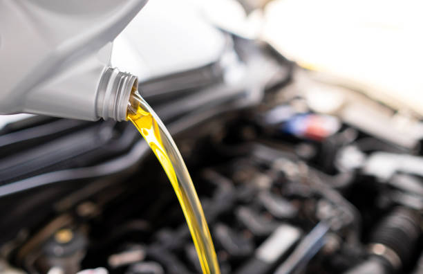 istock Pouring fresh automotive engine oil (lubricating oil, yellow liquid oil) into a motor car with a blurred engine background. Change new oil. Maintenance, service, and energy fuel concept. 1281272291