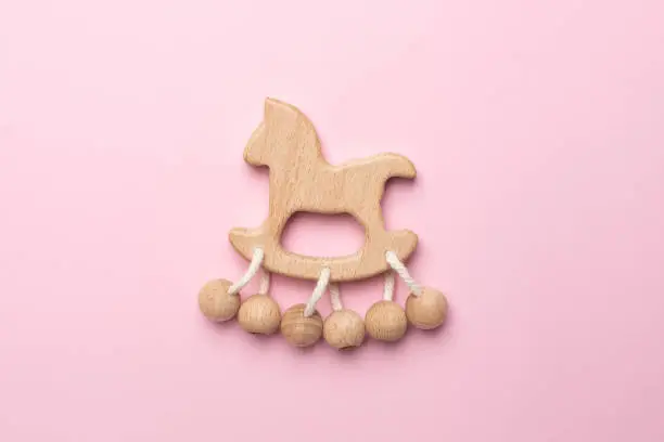 Baby wooden rattle and toy on pink background isolated top view