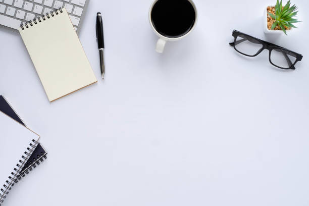 istock Top view above of White office desk table with keyboard, notebook and coffee cup with equipment other office supplies. Business and finance concept. Workplace, Flat lay with blank copy space. 1281275221