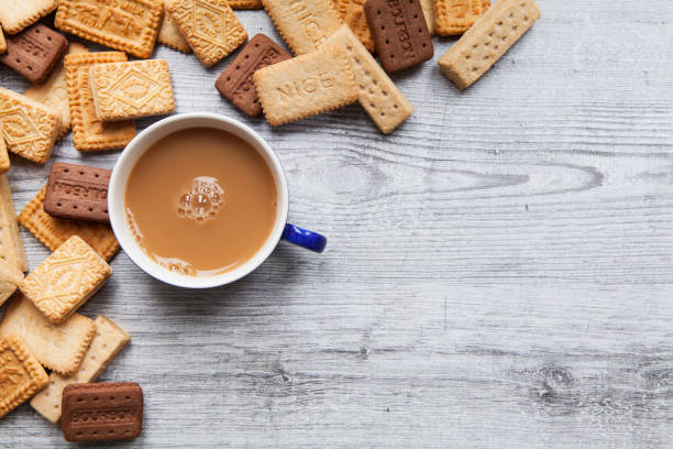 A British biscuit and shortbread selection arranged on a wooden board as a border background with a cup of tea