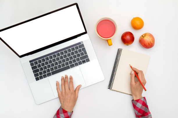 istock Home office workspace mockup. Laptop with blank screen, hands and accessories on white background. Flat lay. Top view 1281282836