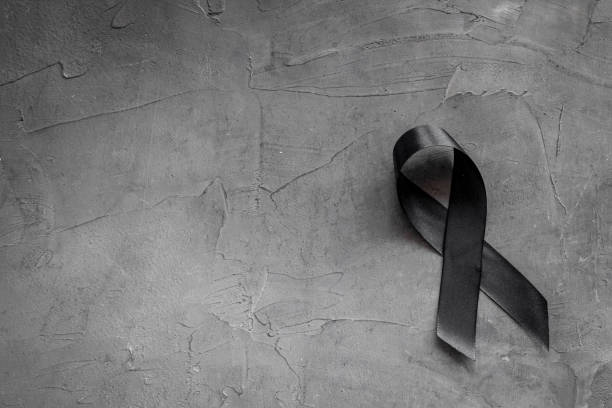 istock Black awareness ribbon on dark background. Mourning symbol 1281286249