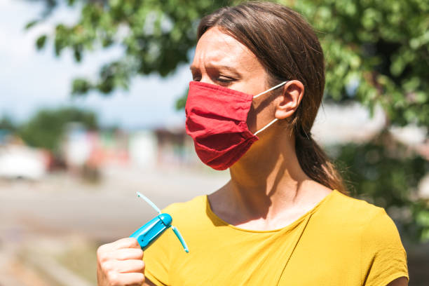 istock young woman cooling down with hand held ventilator while wearing a protective face mask 1281286256