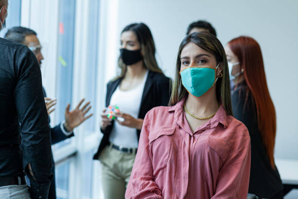istock Executive looks at the camera in a portrait while wearing her mask just like her office colleagues during the meeting 1281286661