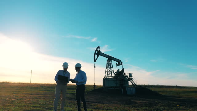 Two engineers inspecting oil field equipment