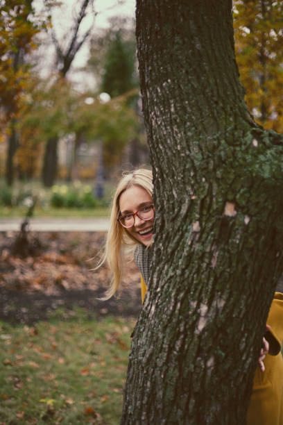 istock Blonde with glasses peeking out from behind tree 1281287488