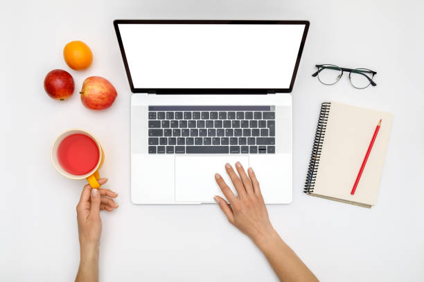 istock Home office workspace mockup. Laptop with blank screen, hands and accessories on white background. Flat lay. Top view 1281288816