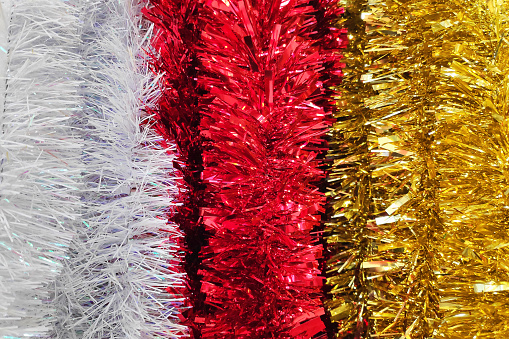 Close-up on a stack of white, red and gold Christmas tinsels.