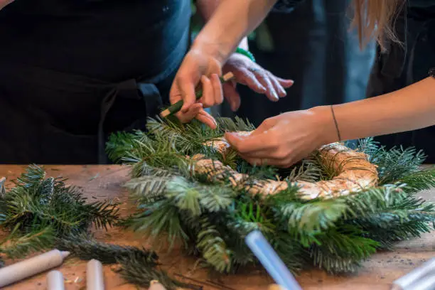 straw round base, scissors and green twigs components in human hands in action