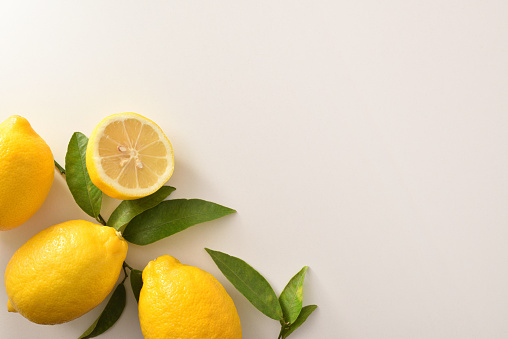 Group of lemons with leaves and section of a lemon on white table. Top view.Horizontal composition.