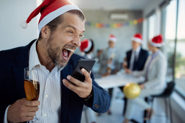 hombre de negocios borracho gritando por teléfono celular mientras hace una llamada telefónica durante la fiesta de navidad en la oficina. - fiesta en la oficina fotografías e imágenes de stock