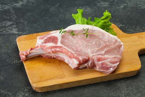 Raw pork bone steak over wooden background