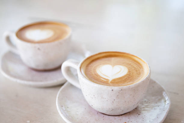 istock Two Cups of hot cappuccino on white wooden table background. 1281296427
