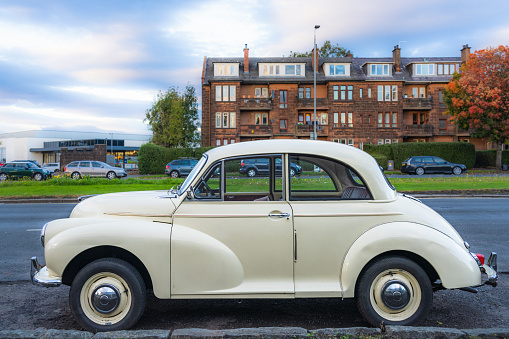 Side view of a cream coloured vintage Morris Minor. The cars were designed in the UK, and produced from 1948 to 1971.