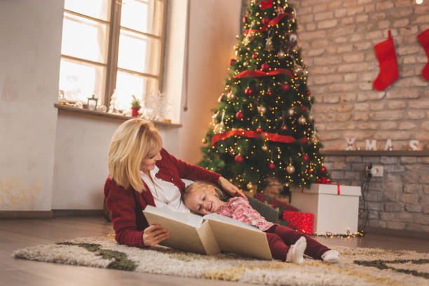 istock Mother and daughter reading a book on Christmas day 1281297271
