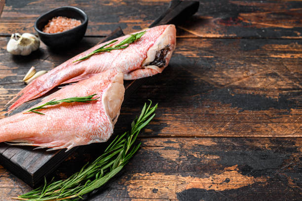 istock Whole raw fresh red perch or seabass fish.  Dark wooden background. Top view. Copy space 1281297350