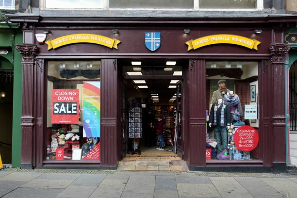 Scottish Souvenir Shop Closing Down on the Royal Mile Edinburgh, Scotland - 20 October 2020 closing down sale and welcome back safety measures signs at a branch of Edinburgh Woollen Mill high street shops chain with customers in applying hand sanitiser closing down sale stock pictures, royalty-free photos & images