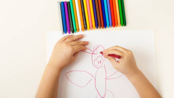 istock hild draws on paper wax crayons beautiful drawing on white background 1281299052