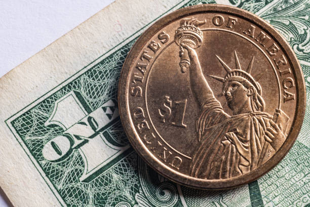 istock One dollar coin on the background of one dollar bill 1281300328