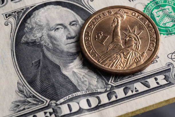 istock One dollar coin on the background of one dollar bill 1281300349