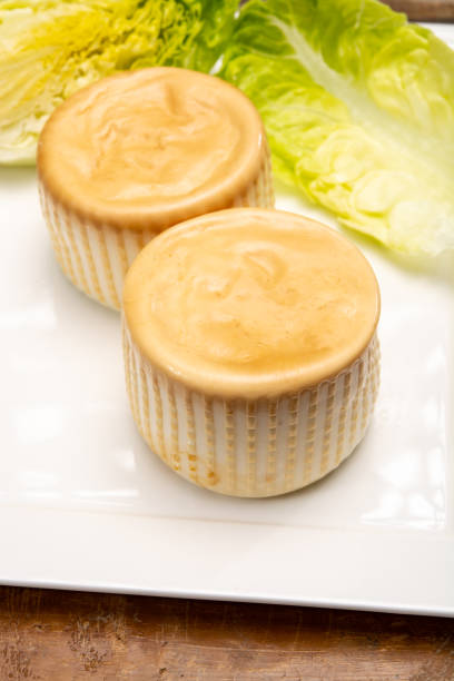 The pieces of cheese in a plate on the wooden table with the blurred background