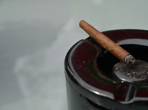 Cigarette buts in a glass ashtray, a cigarette lighter  and a cup of coffee on the table. Nikon D800, full frame, XXXL.