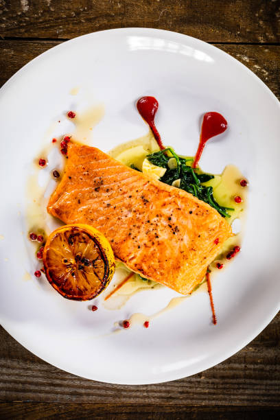 istock Fried salmon fillet and vegetables served on wooden table 1281306236