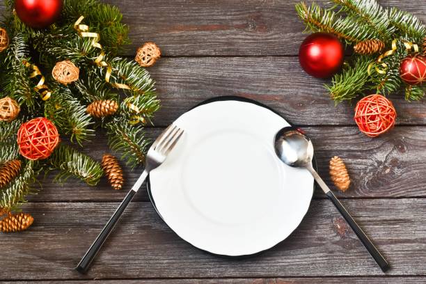 istock Christmas dinner. Christmas Day. Christmas branches with white empty plate,red napkin and cutlery on wooden background. Christmas day. New Year background. Copy space, flat lay. 1281307479