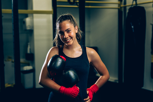 woman holding boxing gloves and posing in gym