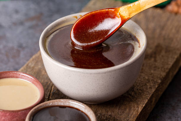 tahini und molasses / türkisch tahin pekmez in auf holzbrett. tahini und melasse in einer schüssel gemischt. - molasses stock-fotos und bilder