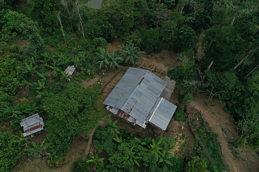 Bird eye view of a small house with a tin roof in the tropical rainforest surrounded by banana plants