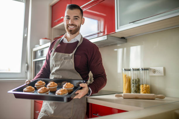 istock Young man wearing apron and preparing muffins in his kitchen 1281315691