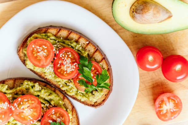 istock toasted bread with avocado paste and fresh tomato. Avocado mixed with lemon juice is spread on bread.  health food concept, vegan, vegetarian 1281319085