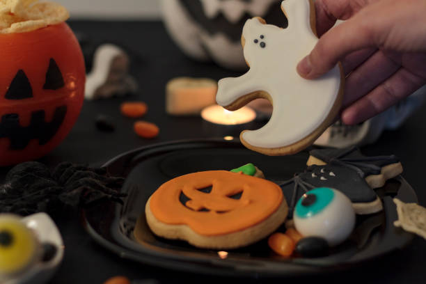 istock Woman holding a ghost cookie from halloween party table 1281319158