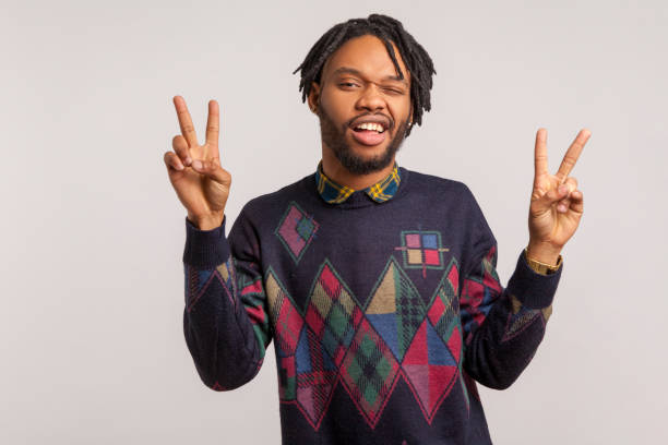 istock Funny african man with beard and dreadlocks having fun winking and showing peace gesture with fingers with toothy smile on face, teasing 1281323535