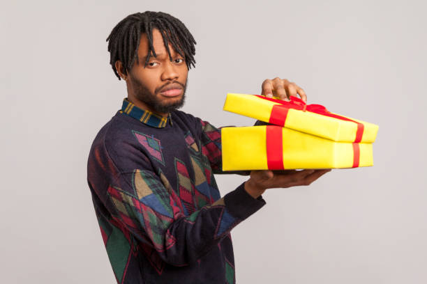 istock Unhappy disappointed african guy with dreadlocks holding unpacked gift box with frustrated dissatisfied face, upset with present 1281323539